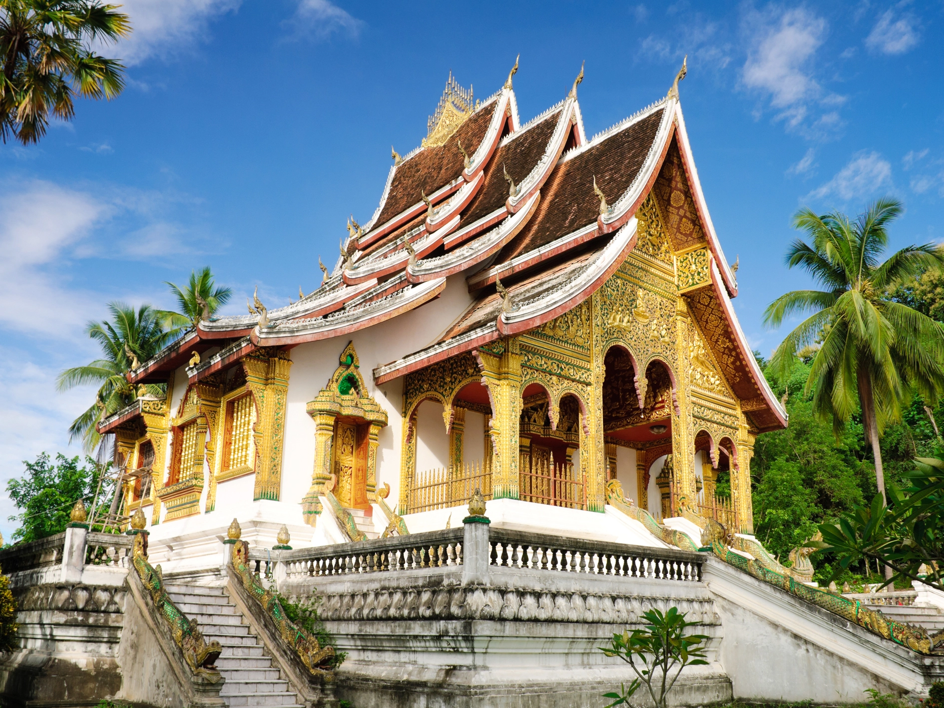 An ornate Buddhist temple with a layered roof and gilded facade in Luang Prabang