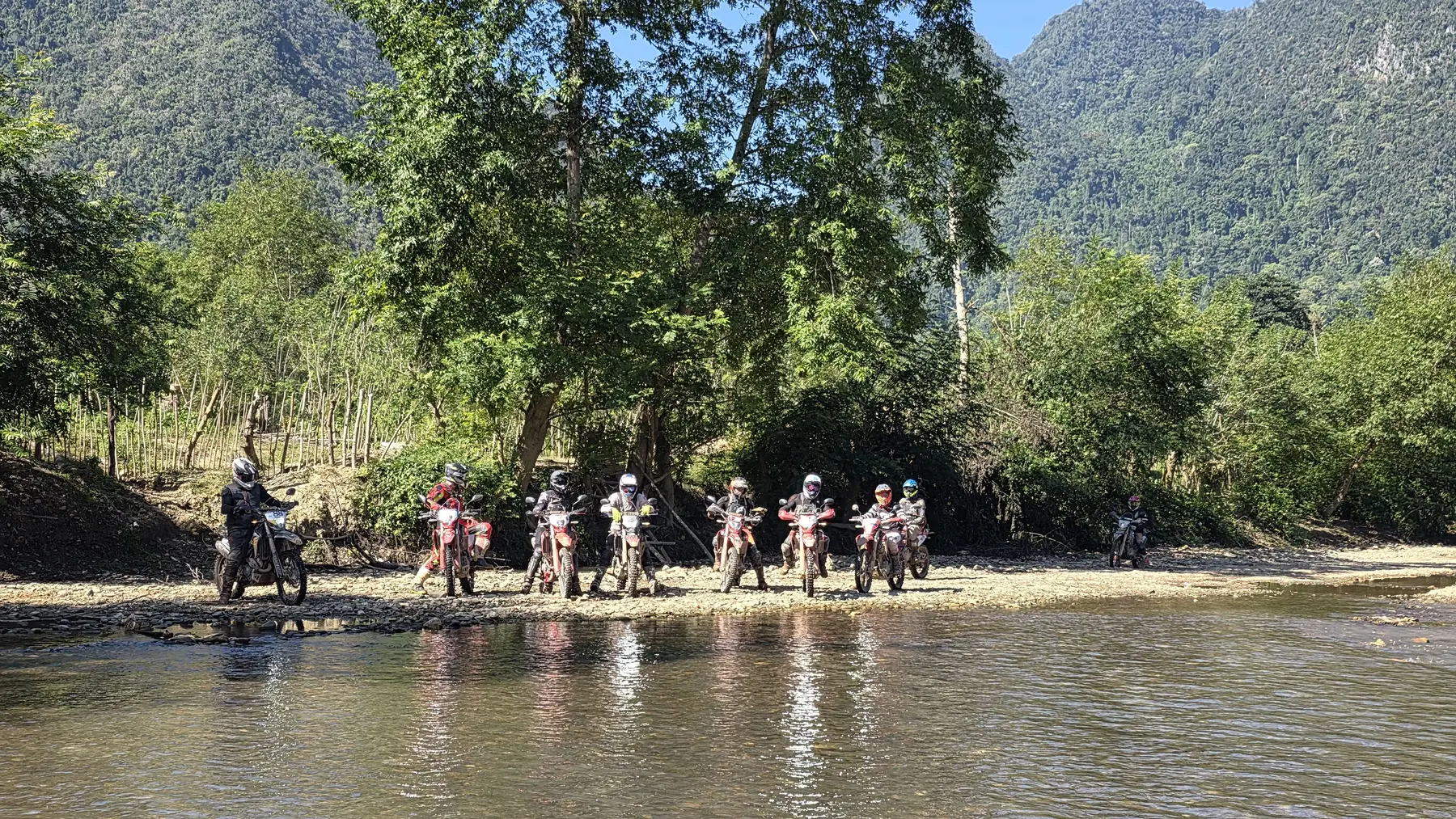 Dirt bike riders preparing for a river crossing in northern Laos