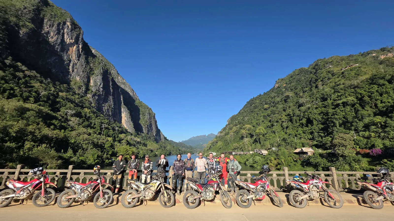 A riding group beside a river framed by limestone mountains.