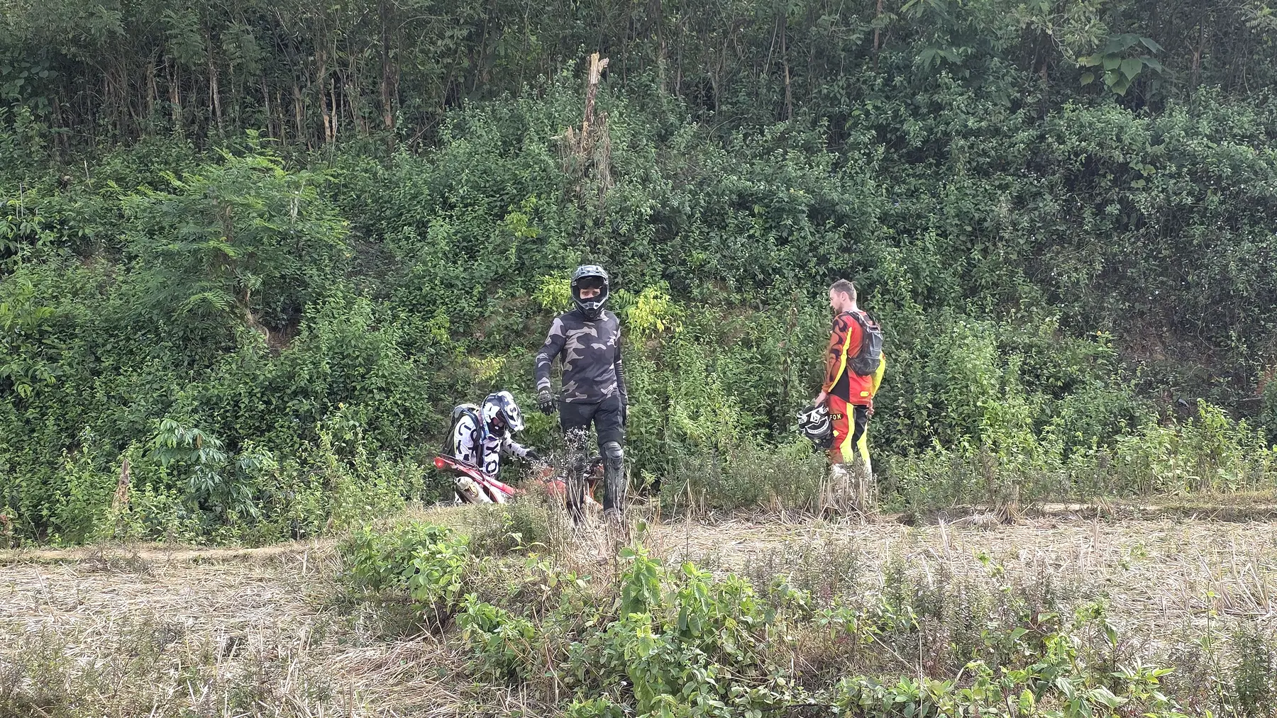 Dirt bike riders crossing remote open country in northern Laos